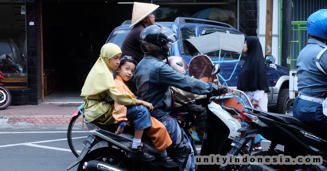 Indonesian father and children riding together on a motorcycle.
